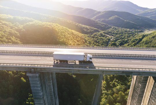 trucks on highway in mountain at sunset aerial view